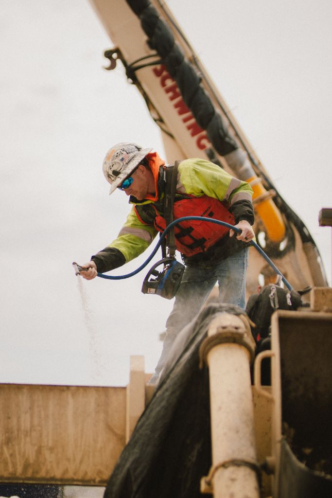 Worker managing concrete hose on construction platform